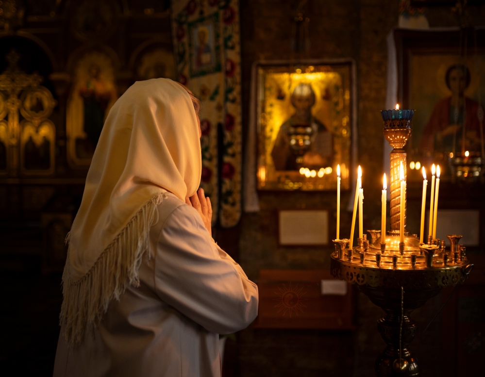 Християнська молитва біля ікони у храмі, українські свічки горять — живий зв’язок із рідною духовною традицією